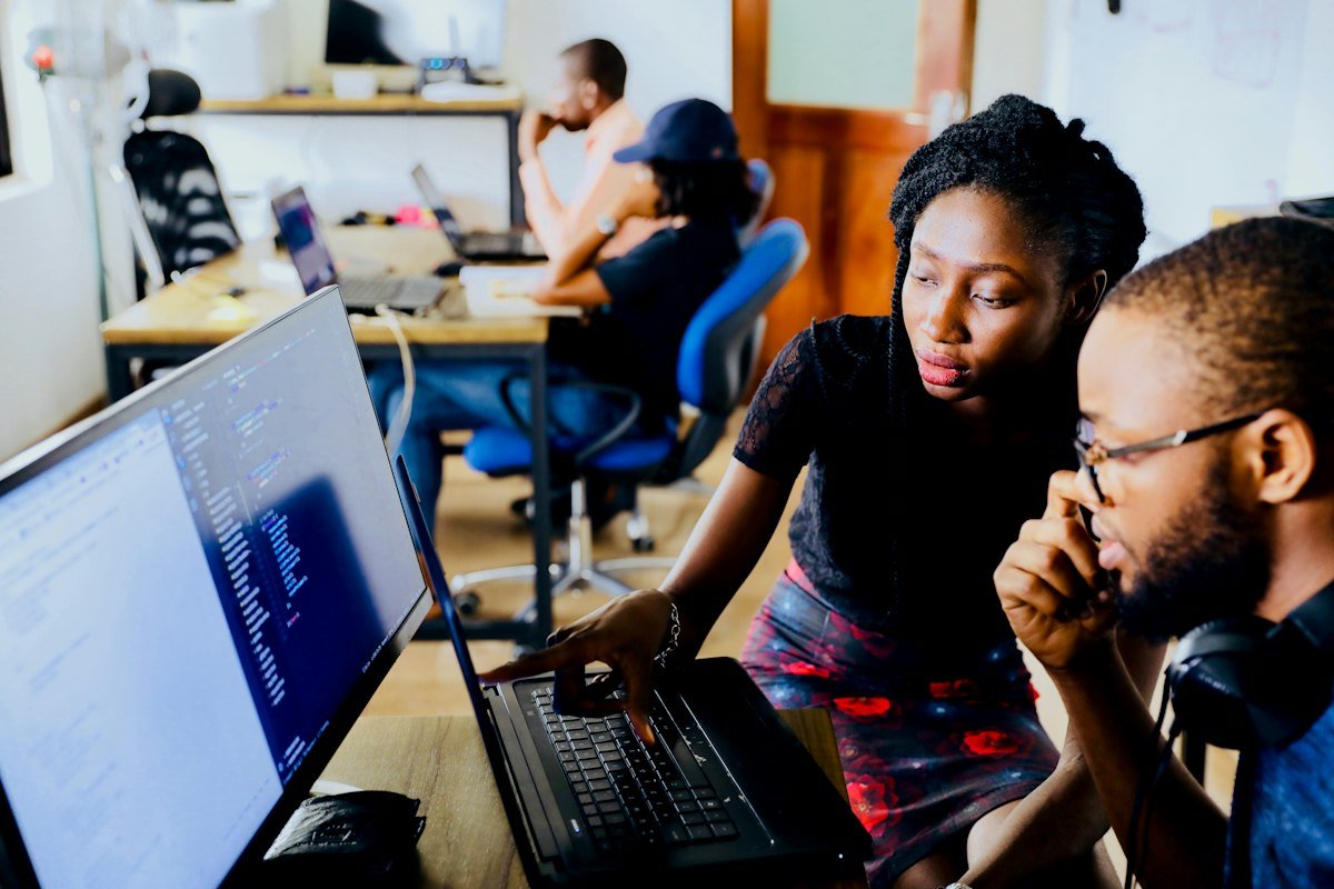 Two software developers reviewing code together on a laptop